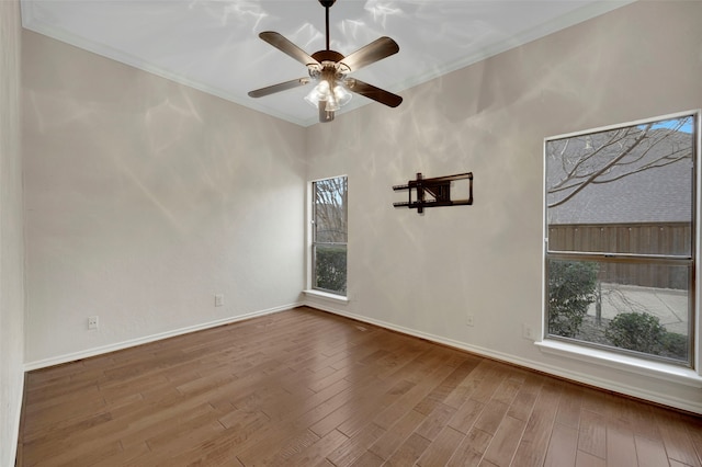 empty room with baseboards, wood finished floors, a ceiling fan, and ornamental molding