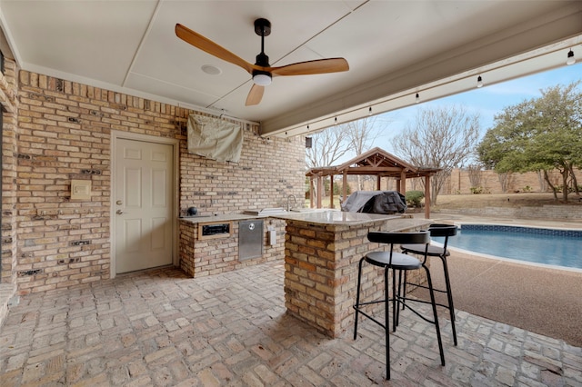 view of patio / terrace with a fenced in pool, exterior kitchen, outdoor wet bar, a gazebo, and a grill