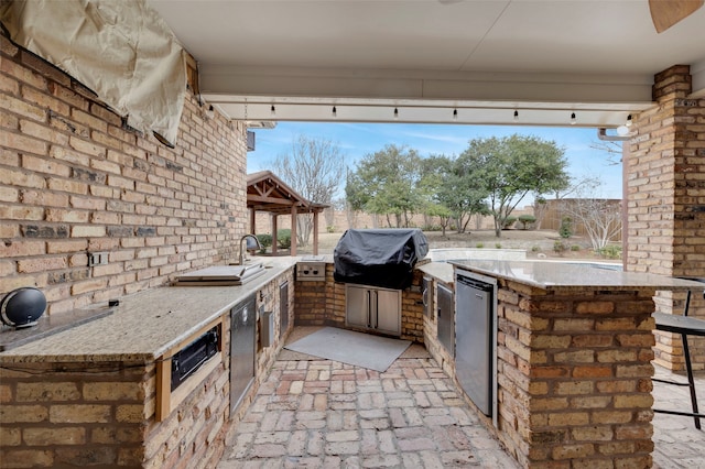 view of patio featuring a gazebo, grilling area, an outdoor kitchen, and fence