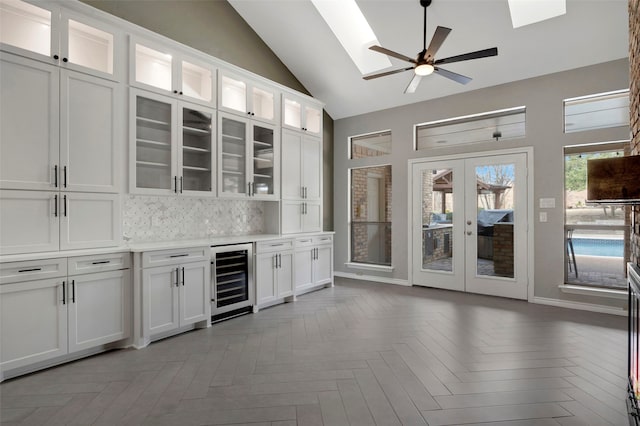 bar with tasteful backsplash, wine cooler, french doors, a skylight, and a ceiling fan