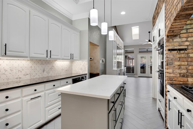 kitchen featuring backsplash, a kitchen island, ornamental molding, white cabinets, and a ceiling fan