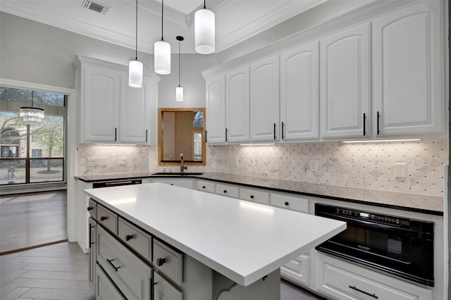 kitchen featuring a sink, oven, ornamental molding, and white cabinetry