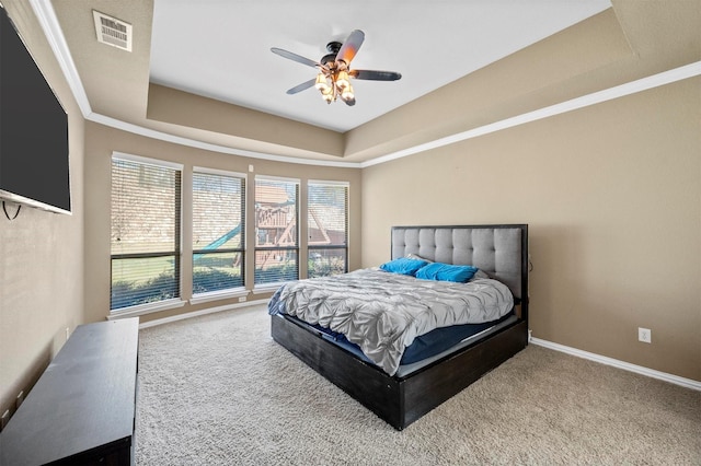 carpeted bedroom featuring visible vents, a ceiling fan, baseboards, crown molding, and a raised ceiling