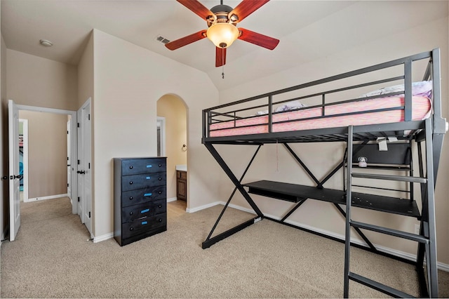 bedroom featuring visible vents, baseboards, vaulted ceiling, light carpet, and arched walkways