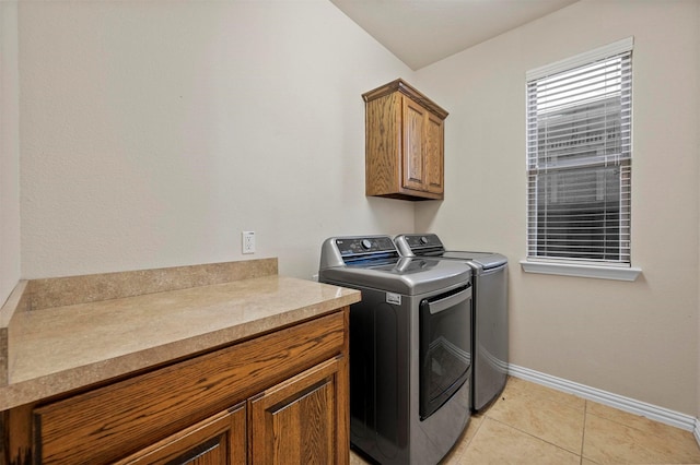 laundry room featuring light tile patterned floors, cabinet space, baseboards, and washer and clothes dryer