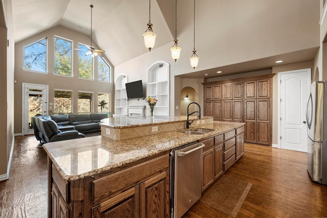 kitchen featuring built in shelves, dark wood-type flooring, a sink, stainless steel appliances, and brown cabinetry