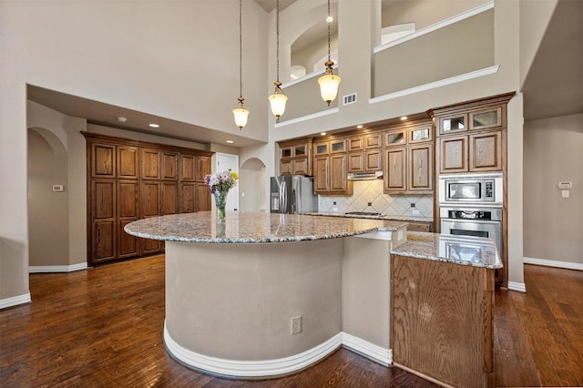 kitchen featuring stainless steel appliances, arched walkways, dark wood-type flooring, and visible vents