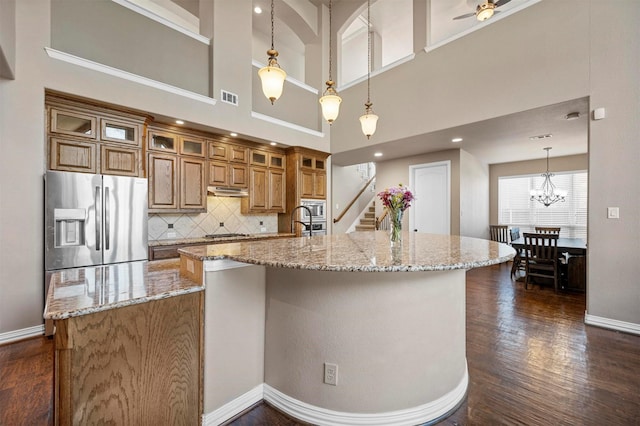 kitchen featuring visible vents, brown cabinets, dark wood-type flooring, stainless steel appliances, and a large island with sink