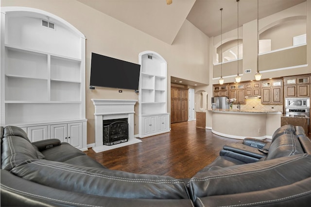 living area with a fireplace, dark wood-style floors, visible vents, and baseboards