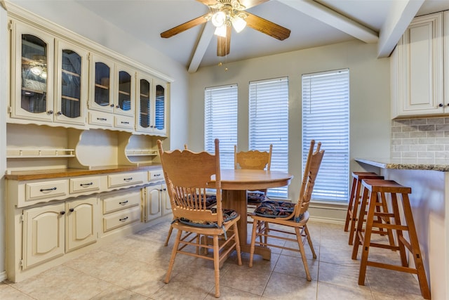 dining area featuring beamed ceiling, light tile patterned flooring, a ceiling fan, and plenty of natural light