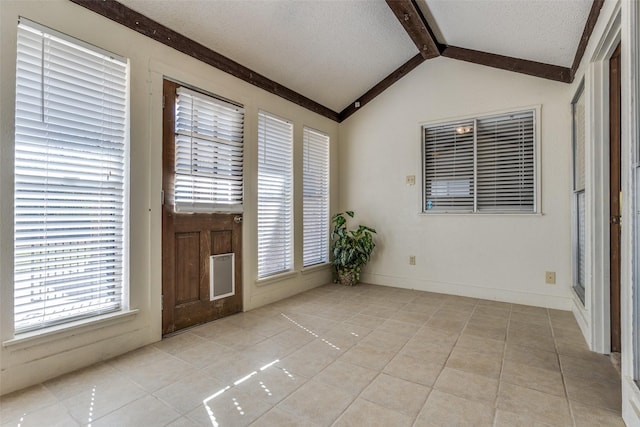 entryway with light tile patterned floors, a textured ceiling, vaulted ceiling with beams, and baseboards