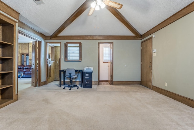 unfurnished office featuring a ceiling fan, vaulted ceiling with beams, light colored carpet, and a textured ceiling