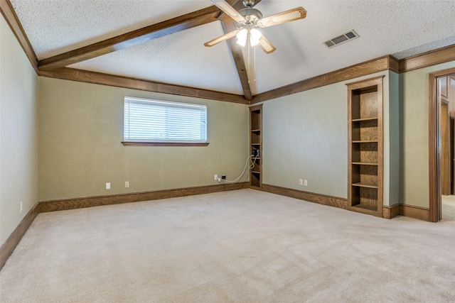 spare room featuring visible vents, lofted ceiling with beams, carpet flooring, a textured ceiling, and a ceiling fan