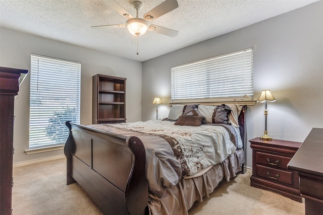 bedroom with baseboards, light colored carpet, a textured ceiling, and a ceiling fan