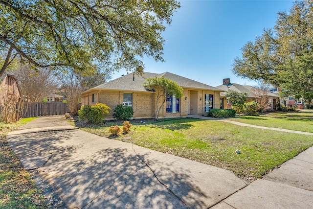 single story home featuring fence, roof with shingles, concrete driveway, a front lawn, and brick siding