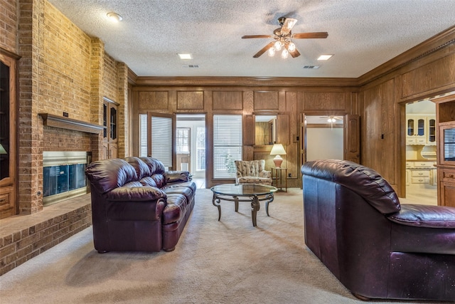 living area featuring light carpet, a textured ceiling, a fireplace, and a ceiling fan