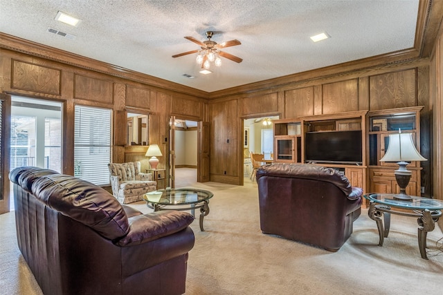 living room featuring visible vents, wooden walls, crown molding, light colored carpet, and ceiling fan