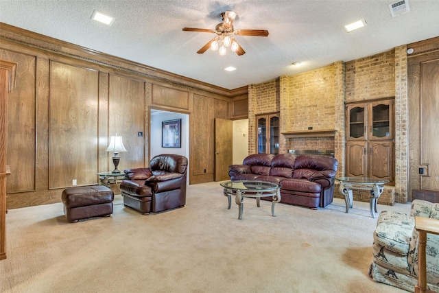 carpeted living area with visible vents, a ceiling fan, a textured ceiling, wood walls, and crown molding