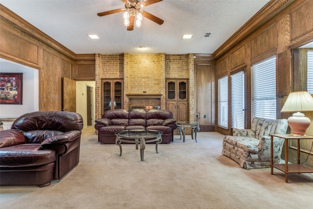 living area featuring a ceiling fan, visible vents, ornamental molding, a textured ceiling, and light carpet