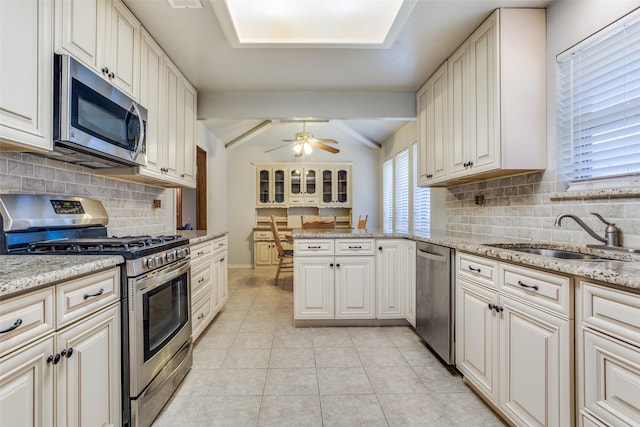 kitchen with vaulted ceiling with beams, light tile patterned floors, appliances with stainless steel finishes, a peninsula, and a sink