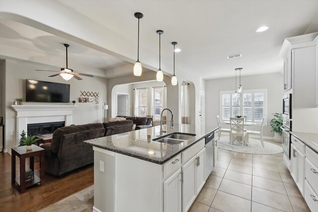108 Zion Ln, Forney, TX 75126 - kitchen featuring a sink, arched walkways, dark stone counters, appliances with stainless steel finishes, and a center island with sink