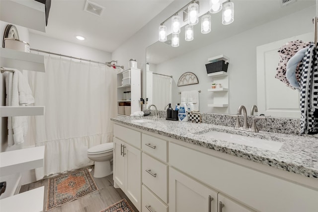 1403 Franklin Ave, Bonham, TX 75418 - bathroom featuring toilet, double vanity, wood finished floors, and recessed lighting