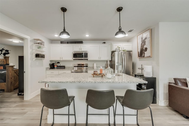 1403 Franklin Ave, Bonham, TX 75418 - kitchen featuring stainless steel appliances, light wood-style floors, white cabinets, a breakfast bar, and recessed lighting