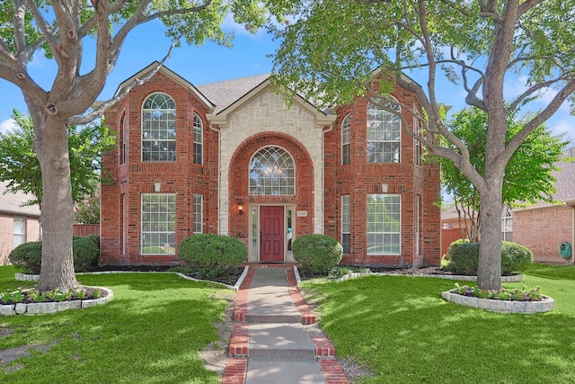 traditional home with a front yard, brick siding, and stone siding