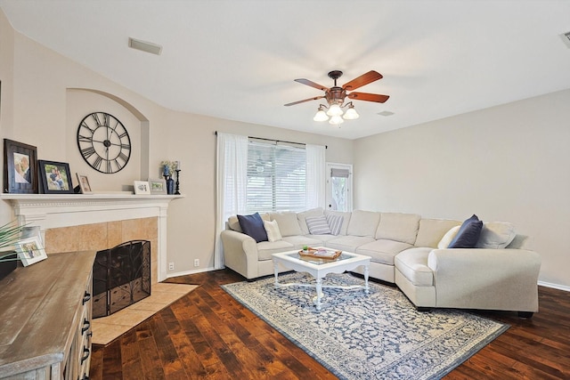 living area with visible vents, hardwood / wood-style floors, baseboards, ceiling fan, and a tile fireplace