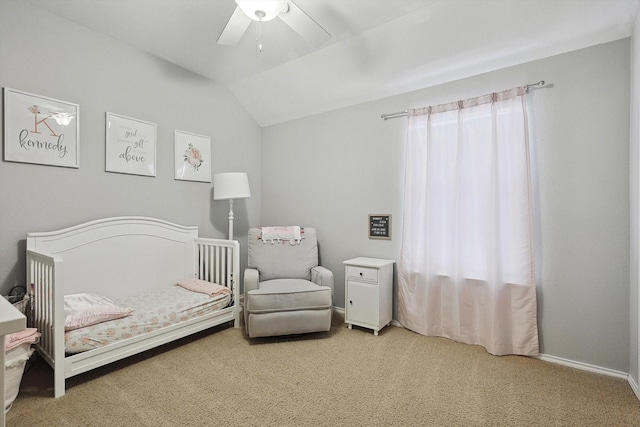 bedroom with a crib, baseboards, ceiling fan, vaulted ceiling, and carpet flooring