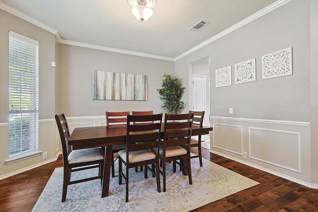 dining area featuring a wainscoted wall, visible vents, dark wood-type flooring, crown molding, and a decorative wall