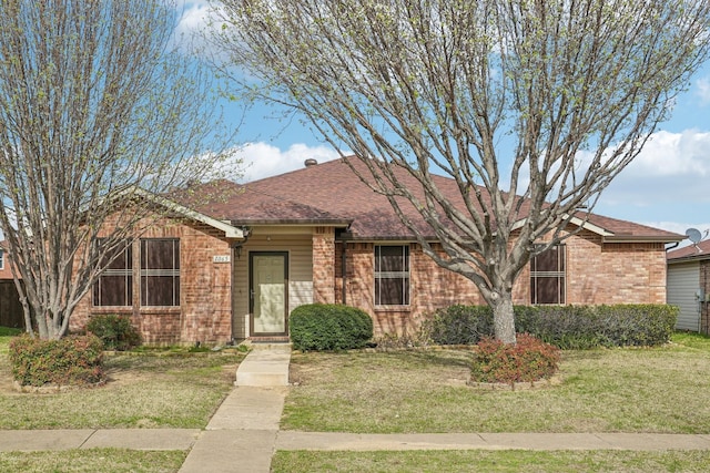 single story home featuring a front yard, brick siding, and roof with shingles