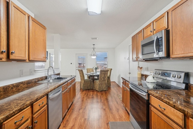 kitchen with a wealth of natural light, light wood-style flooring, appliances with stainless steel finishes, and a sink