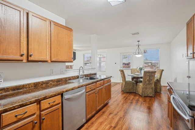 kitchen featuring visible vents, a sink, dark countertops, dark wood finished floors, and stainless steel appliances