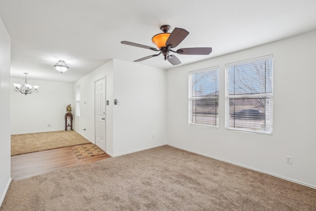 unfurnished room featuring ceiling fan with notable chandelier and carpet floors