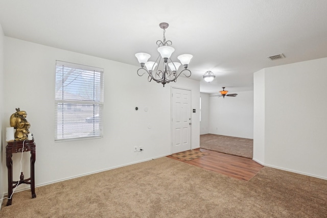 empty room with a chandelier, carpet flooring, and visible vents