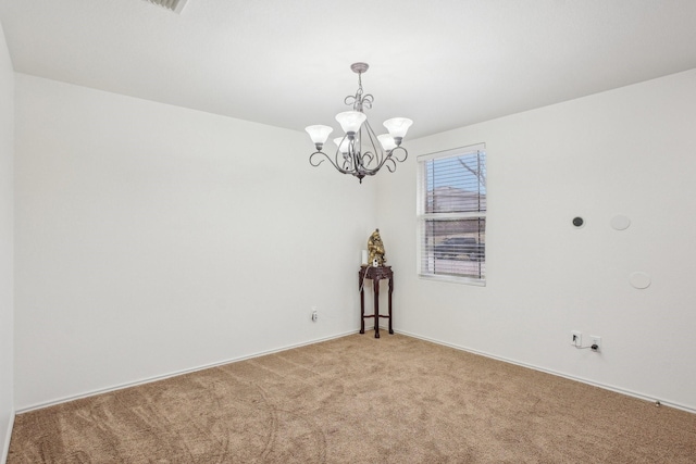 empty room featuring light carpet and a chandelier