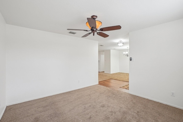 spare room with carpet flooring, ceiling fan with notable chandelier, and visible vents