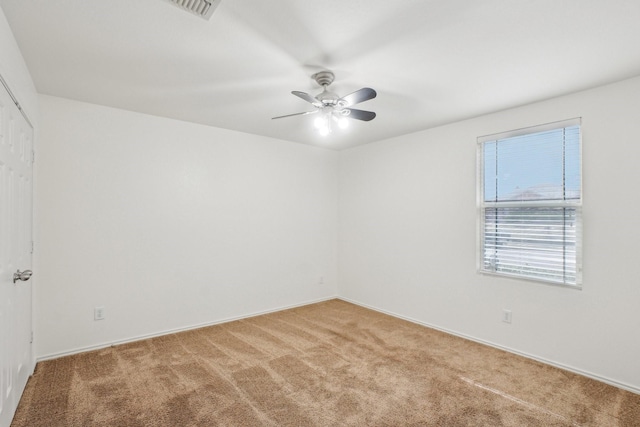 empty room with light colored carpet, visible vents, and ceiling fan