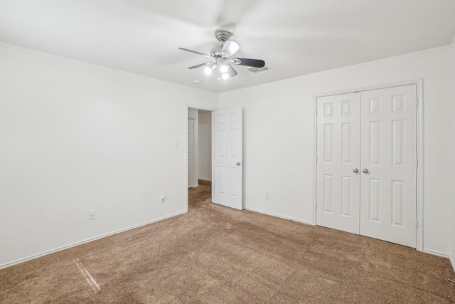 unfurnished bedroom with visible vents, a closet, carpet floors, baseboards, and ceiling fan