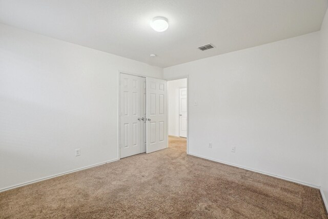 spare room featuring light carpet, visible vents, and baseboards