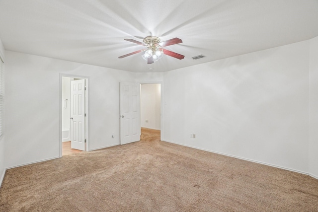 spare room with light carpet, visible vents, and a ceiling fan