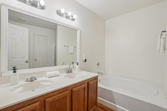 full bath featuring a sink, visible vents, a bath, and double vanity