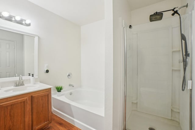 bathroom featuring a stall shower, vanity, and a garden tub