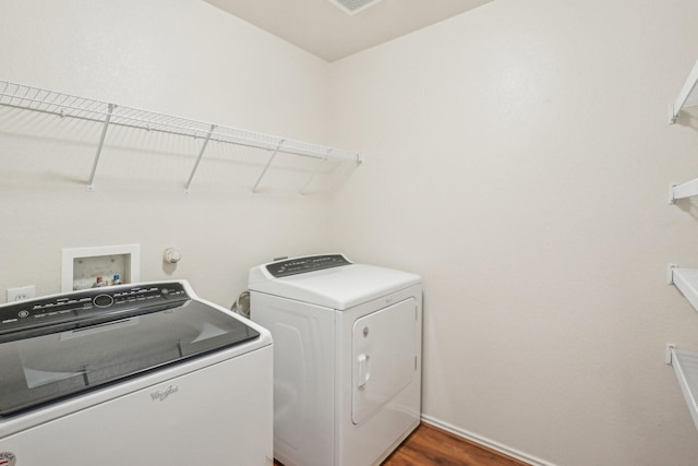 clothes washing area featuring baseboards, independent washer and dryer, wood finished floors, and laundry area