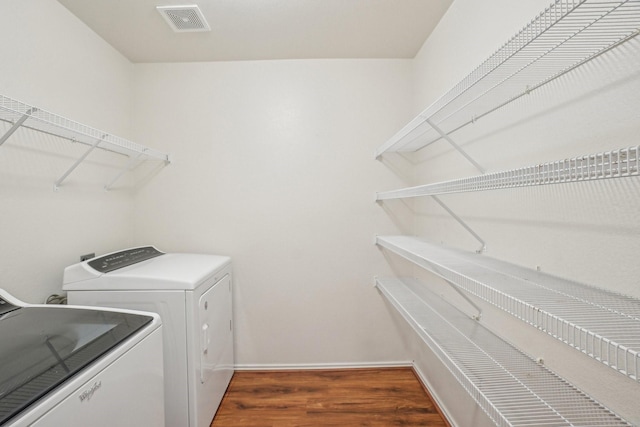 laundry room with visible vents, washer and dryer, wood finished floors, baseboards, and laundry area