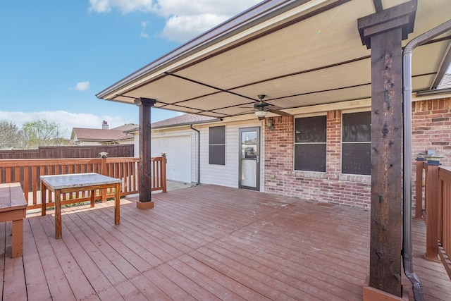 wooden terrace featuring a ceiling fan, fence, and a garage