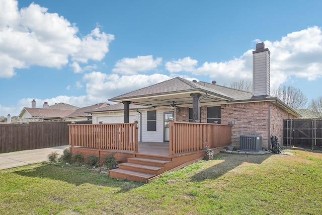 back of property featuring central AC unit, fence, a deck, a lawn, and brick siding