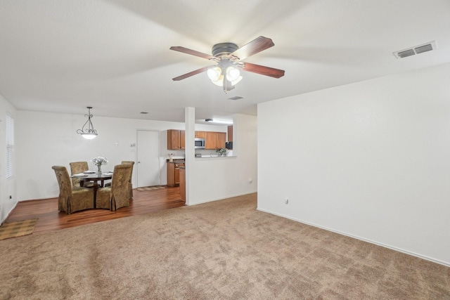 living room with a ceiling fan, light colored carpet, and visible vents