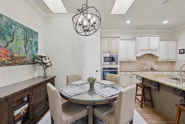 dining area with ornamental molding, recessed lighting, light wood-style floors, a skylight, and a chandelier